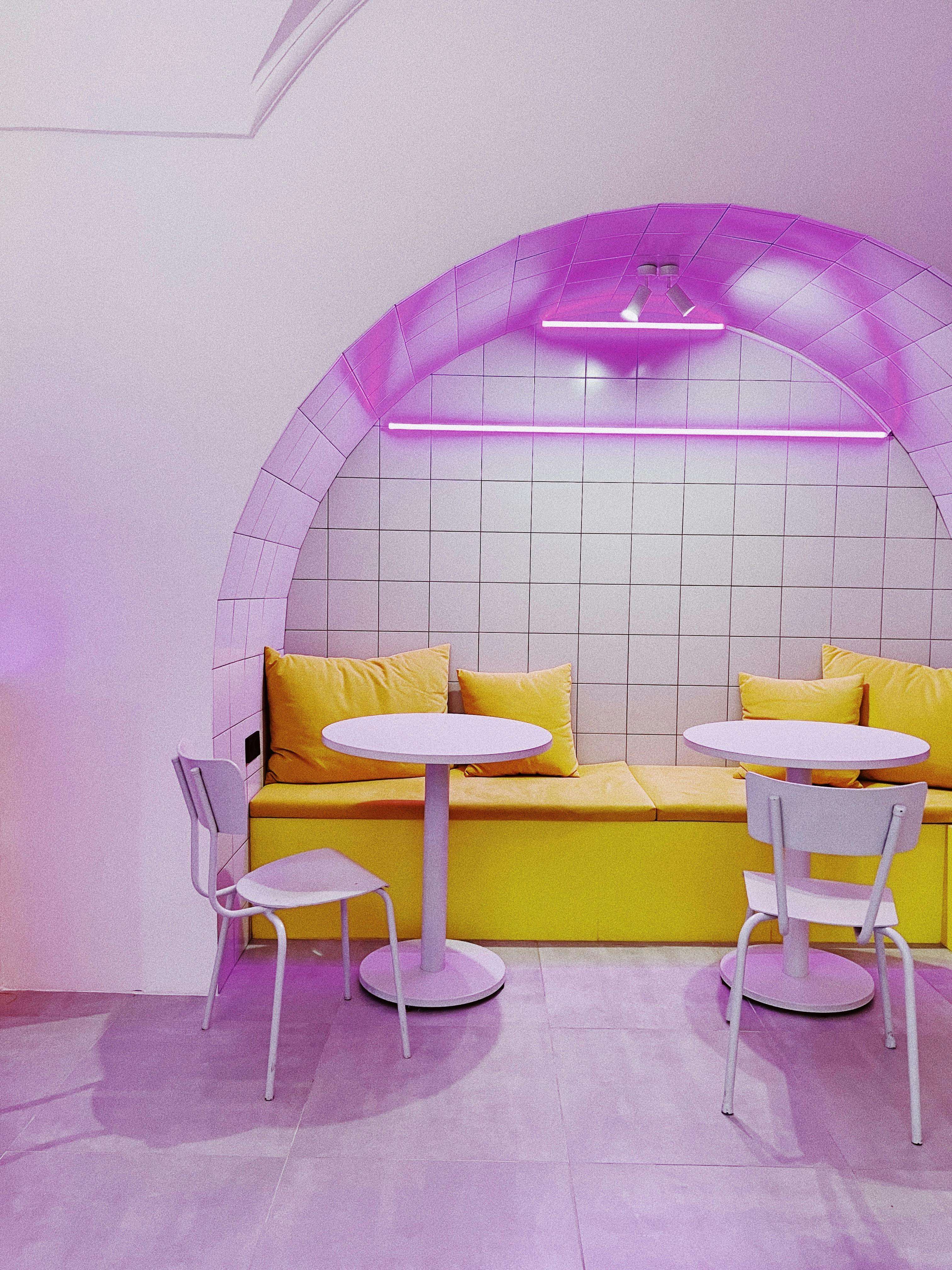 Modern cafe nook with neon lighting and bright yellow cushions, creating a stylish and inviting interior design.