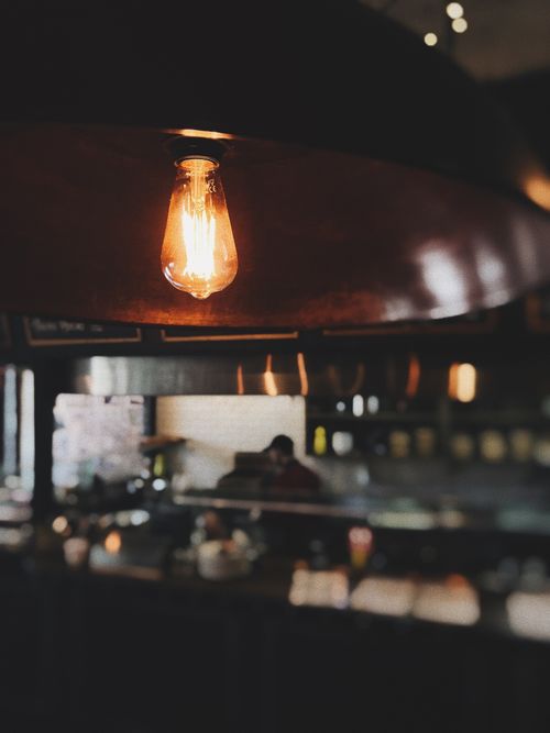 Free Cozy café interior featuring a glowing Edison bulb, creating a warm and modern ambiance. Stock Photo