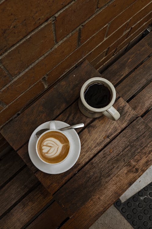 Darmowe zdjęcie z galerii z cappuccino, czarna kawa, drewniany stół