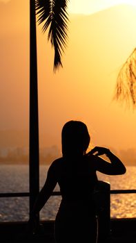 A silhouette of a woman during sunset by the sea in Antalya, Turkey. A serene, golden hour moment.
