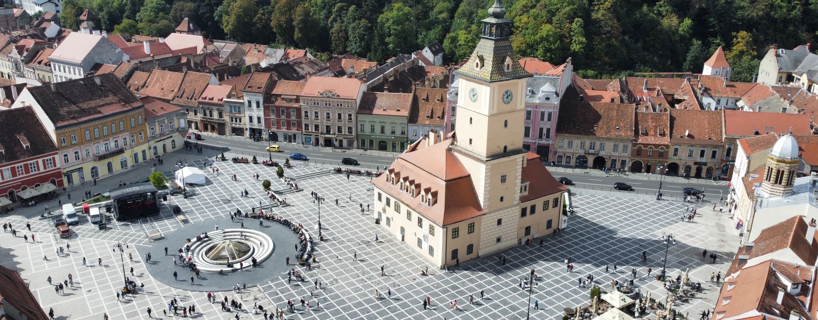 Aerial shot of the vibrant town square in Brașov, showcasing historic architecture and bustling activity.