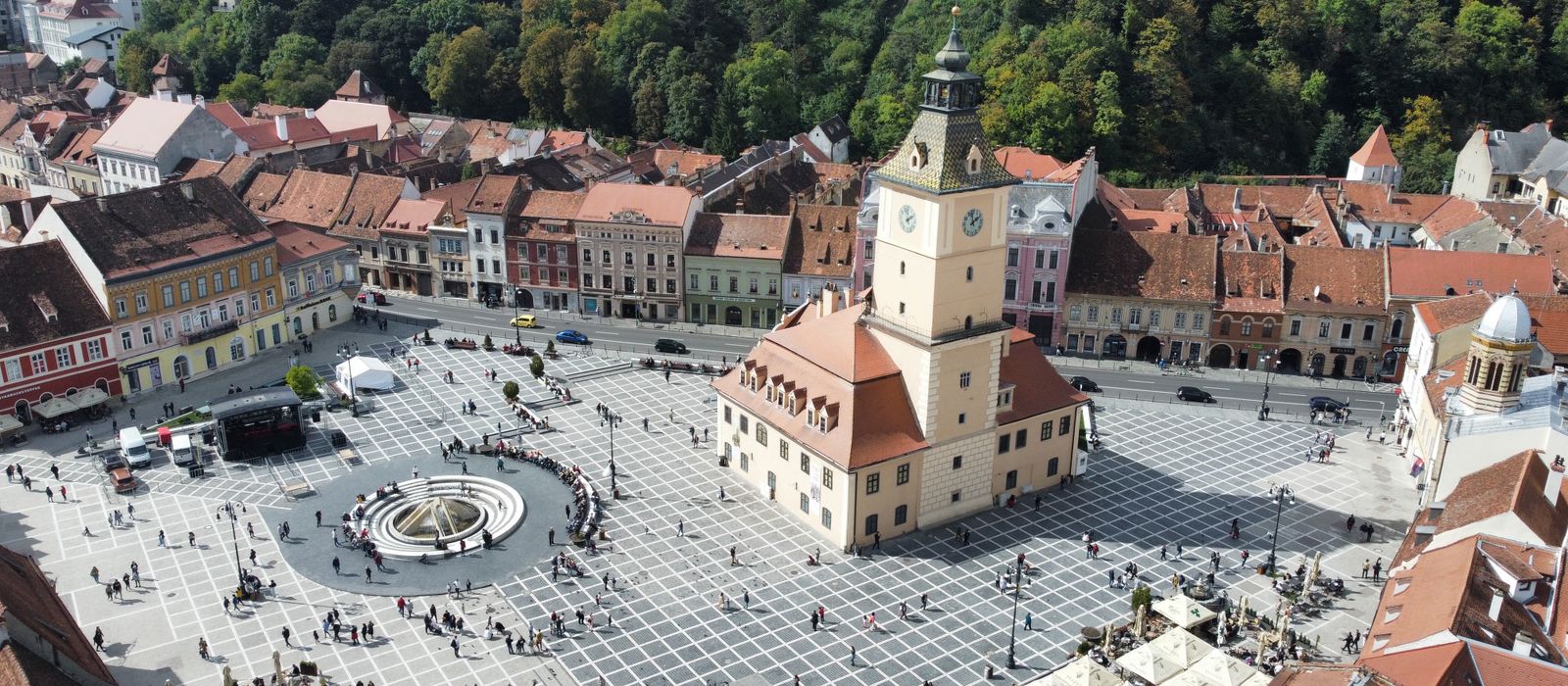 Aerial shot of the vibrant town square in Brașov, showcasing historic architecture and bustling activity.