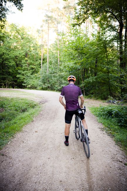 A cyclist pauses on a scenic forest trail during a summer ride.
