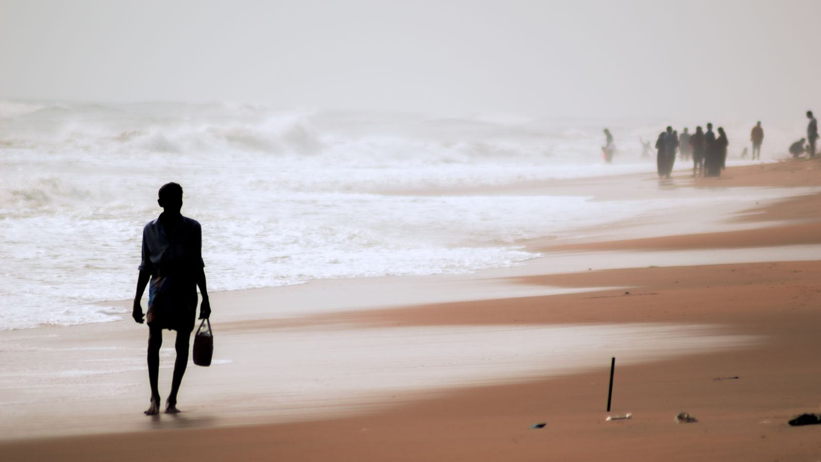 Silhouette of a person standing barefoot on sand, Benin