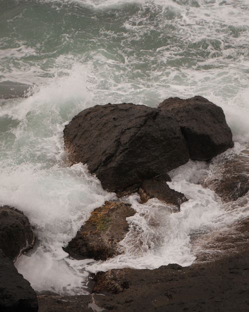 Free Powerful ocean waves crashing against large rocks on a rugged shoreline, capturing the force of nature. Stock Photo