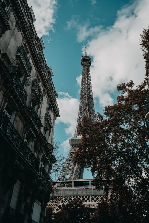 Free Low angle shot of the Eiffel Tower with a blue sky and urban surroundings. Stock Photo