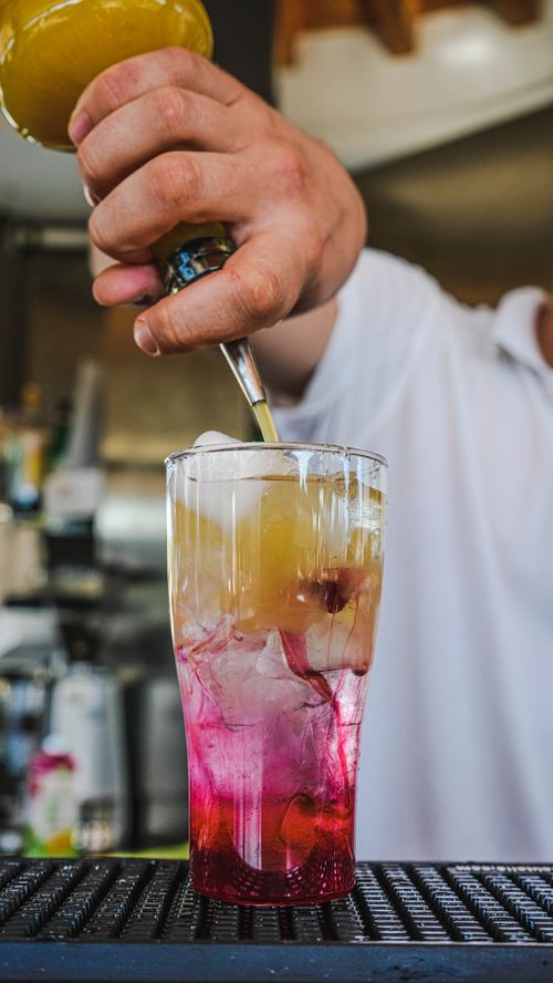 Free Close-up of a colorful cocktail being poured at a bar, showcasing vibrant layers and mixology skills. Stock Photo