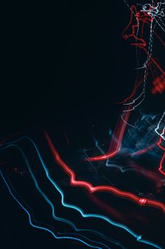 Abstract long exposure photograph featuring vibrant red and blue light streaks against a dark background.