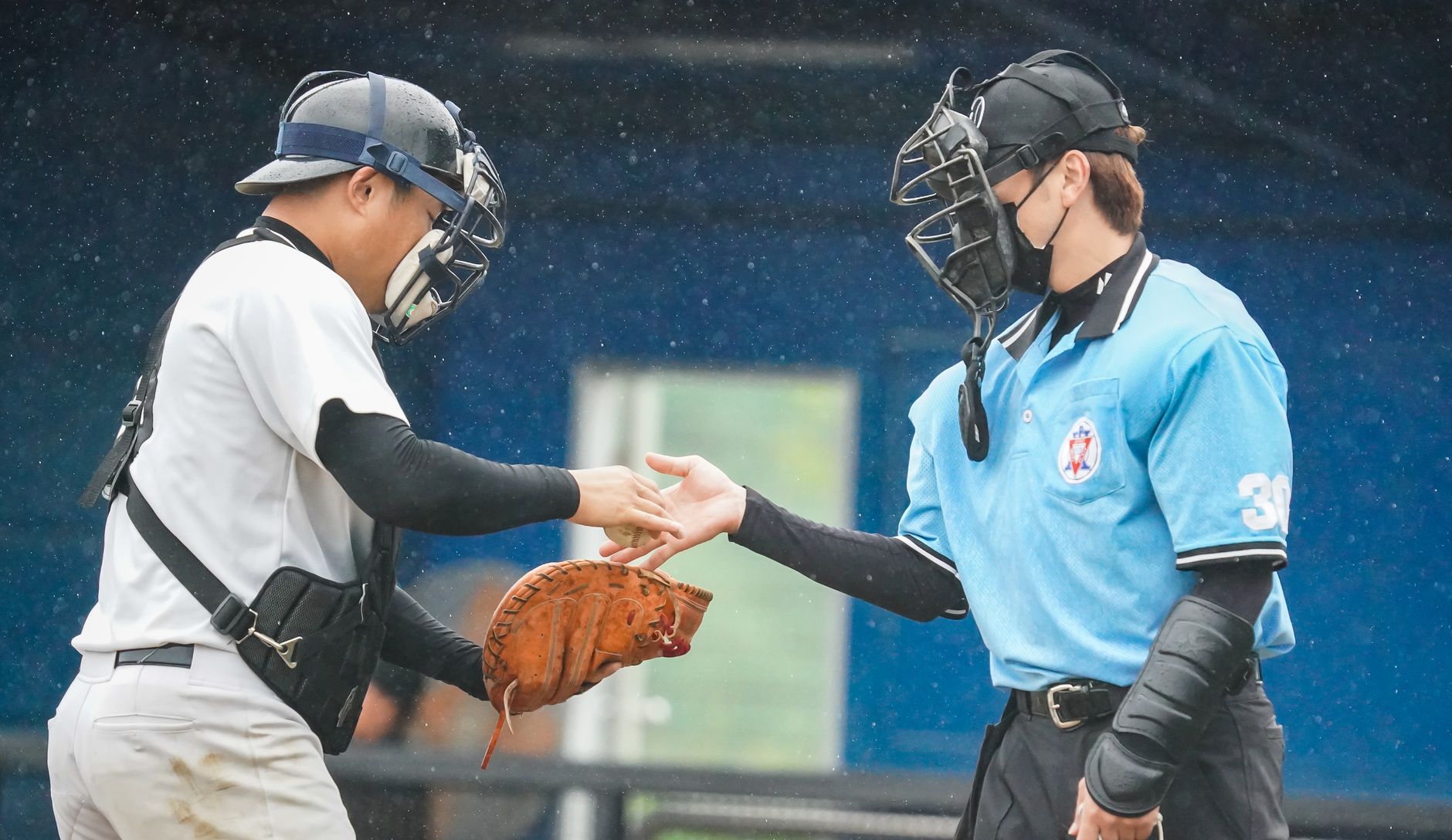Baseball player shaking hands with an umpire on a rainy day.