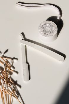 Aesthetic minimalist arrangement of everyday grooming tools with a wireless speaker on a white surface.