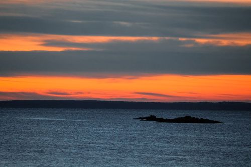 Free Tranquil ocean scene with vibrant sunset hues and dramatic cloud formations. Stock Photo