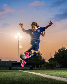 A young girl in sportswear playing soccer on a field at sunset, showcasing talent and energy.