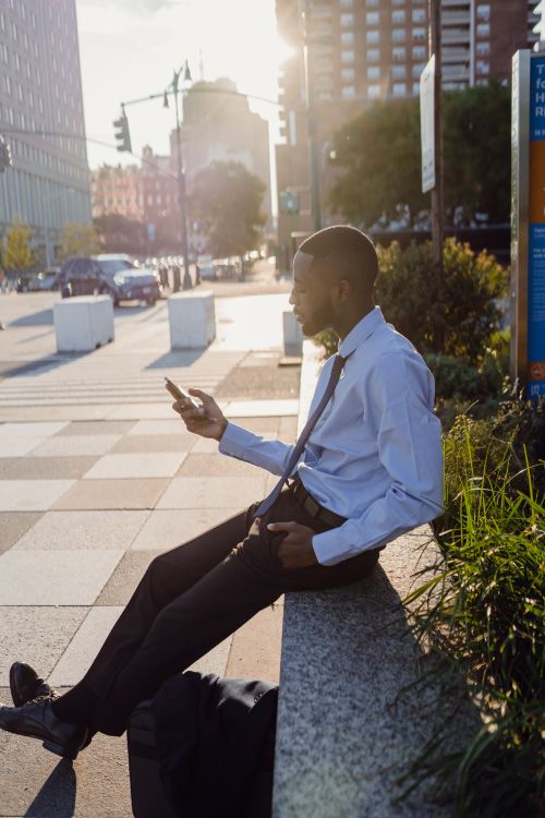 Free Businessman in city park during sunset using smartphone. Stock Photo