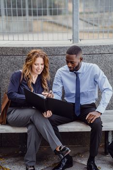 Business colleagues analyzing documents outside, engaged in discussion.
