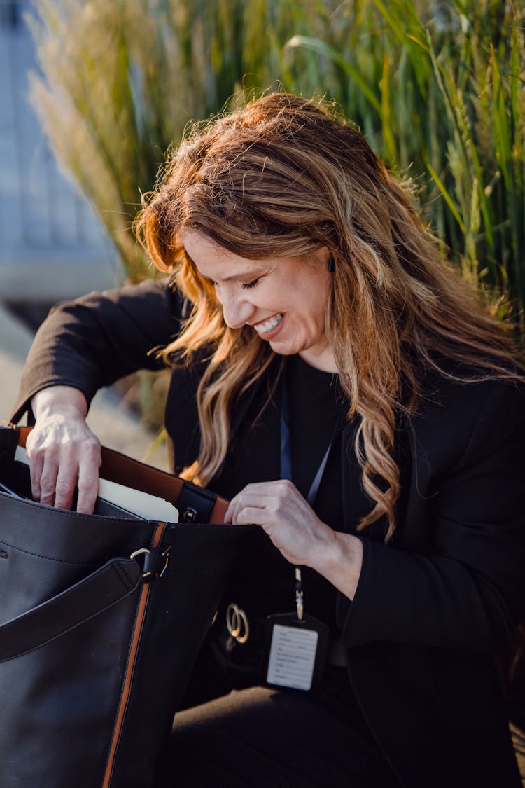 Smiling Woman Searching In Bag Outdoors