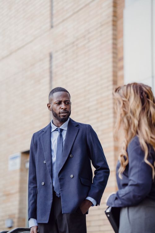 Free Two business professionals engage in conversation outside a building, wearing formal attire. Stock Photo