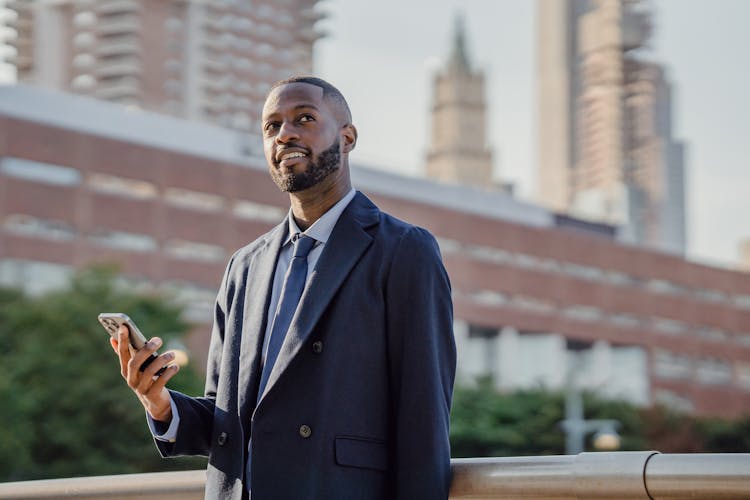 Smiling Businessman Using Cellphone Outdoors