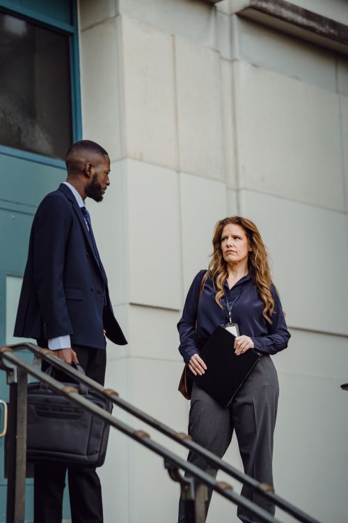 Free Two professionals in formal attire engage in conversation outside a building. Stock Photo
