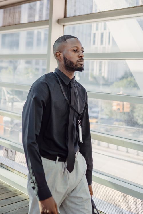 Free A young African American man in elegant attire walking confidently in an urban environment. Stock Photo