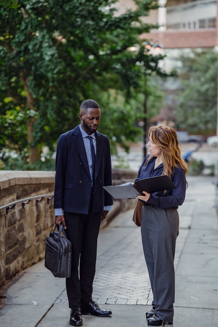 Two People Standing With A Binder In A City