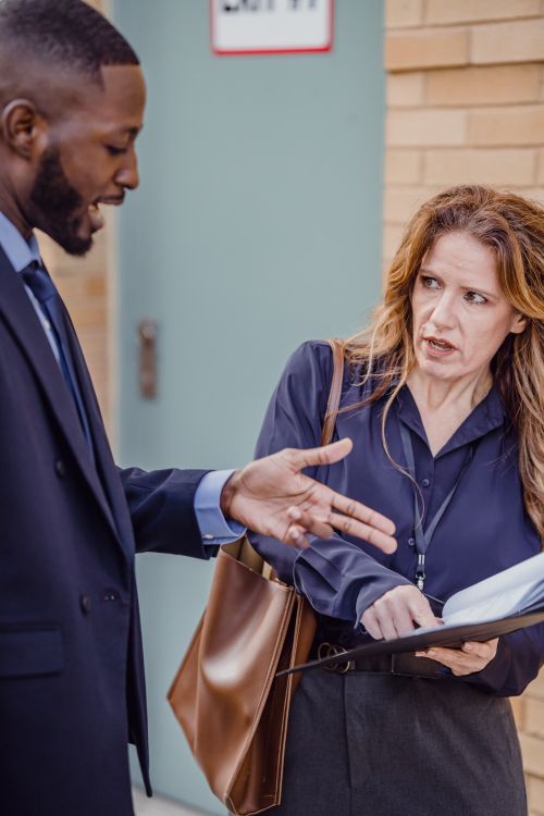 Free Two professionals discussing work outdoors, focusing on paperwork and communication. Stock Photo