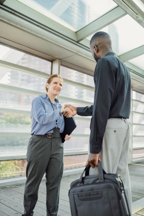 Free Two business professionals shaking hands in a modern cityscape setting, symbolizing cooperation. Stock Photo
