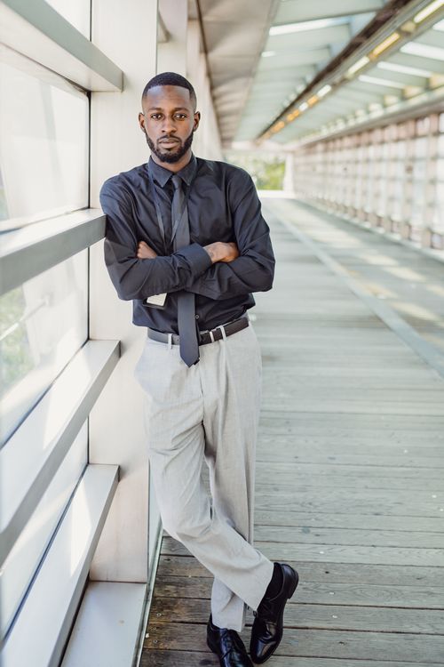 Free Elegant portrait of a man with arms crossed in a modern corridor setting. Stock Photo