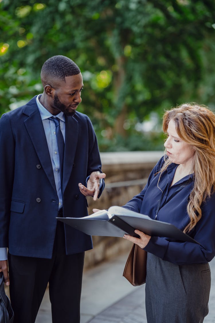 Two People Standing Looking At A Binder