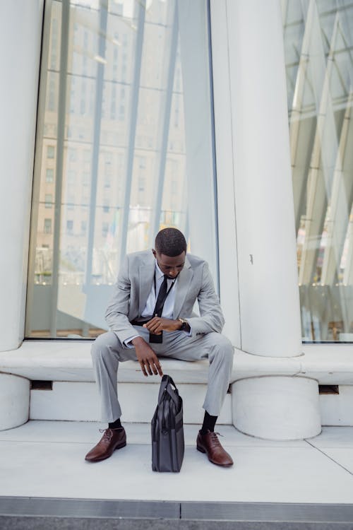 Elegant Office Worker Wearing a Suit Sitting by a White Modern Architecture