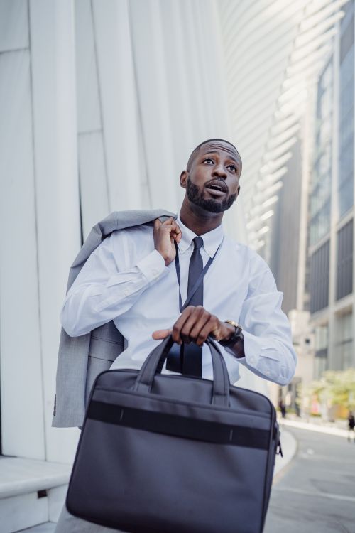 Free A determined businessman in a suit and tie holding a briefcase while walking in the financial district. Stock Photo