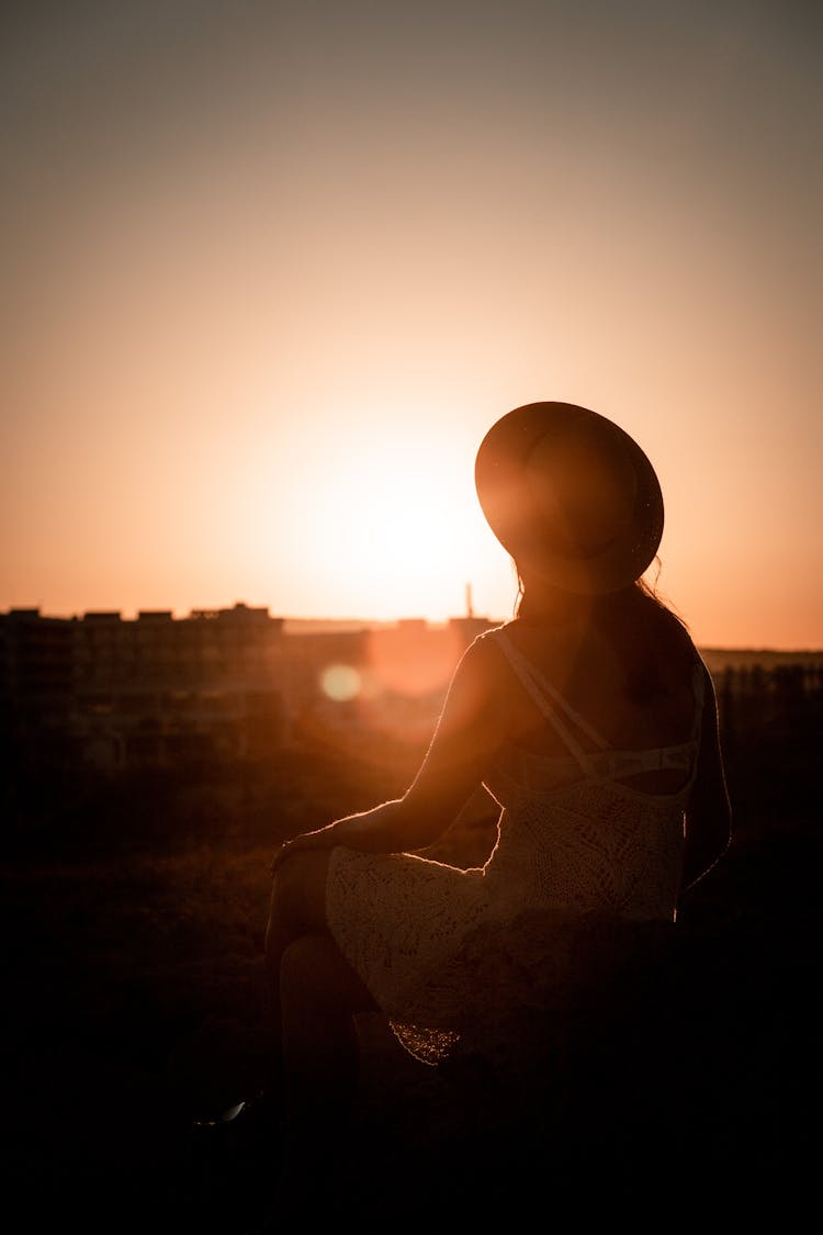 Silhouette Of Woman In Hat At Sunset