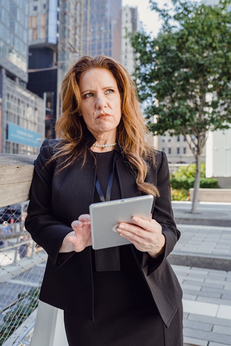 Businesswoman Leaning Against Railing In A City And Calculating Risk