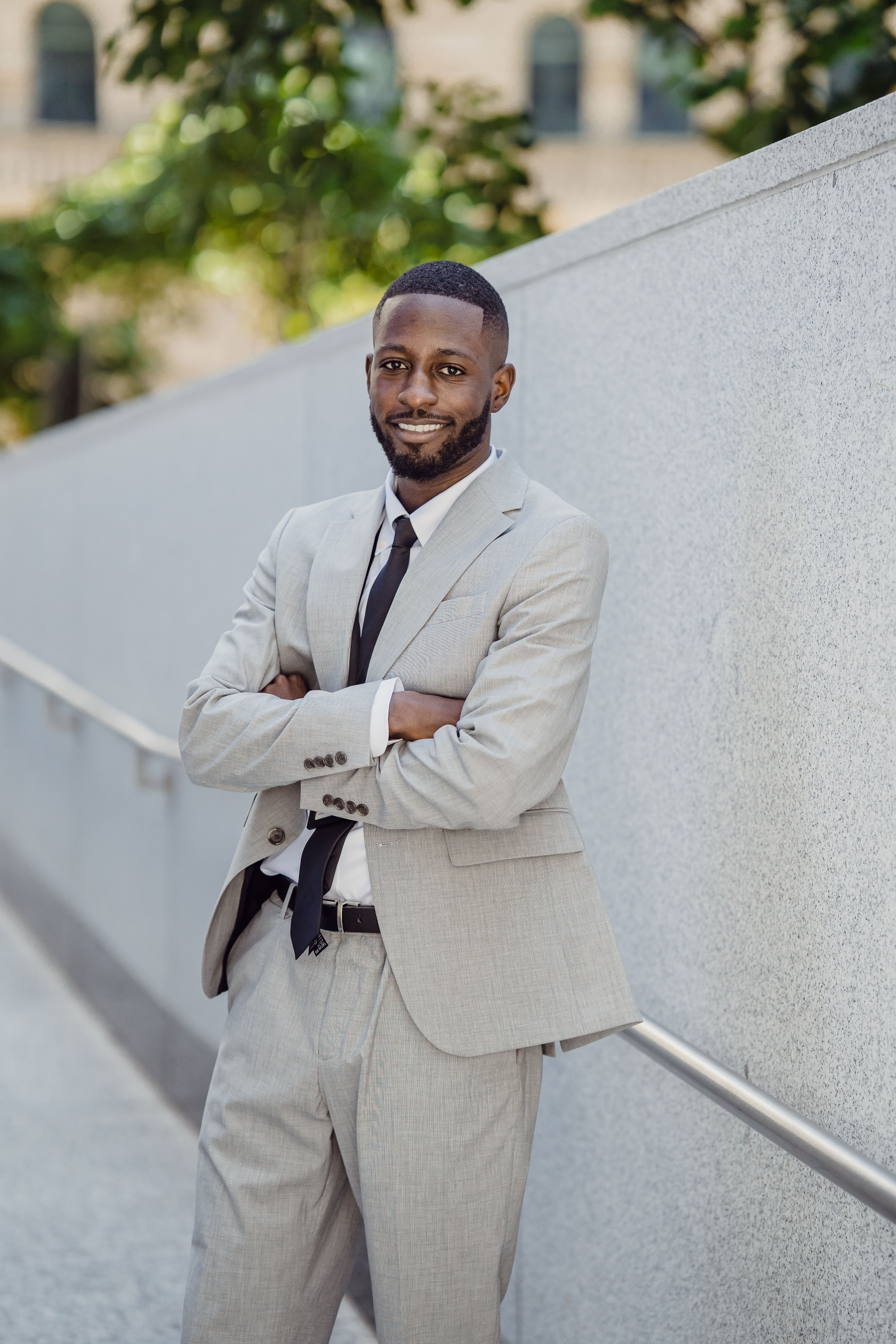 Smiling Man in a Gray Suit Standing with Arms Crossed by a Fence · Free ...