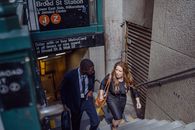 Two business professionals walking up steps from a subway station in New York City.