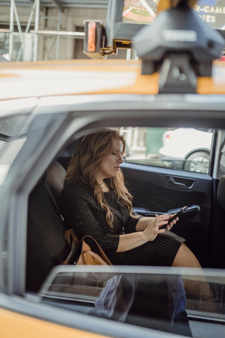 Woman Sitting In A Taxi And Using Her Phone 