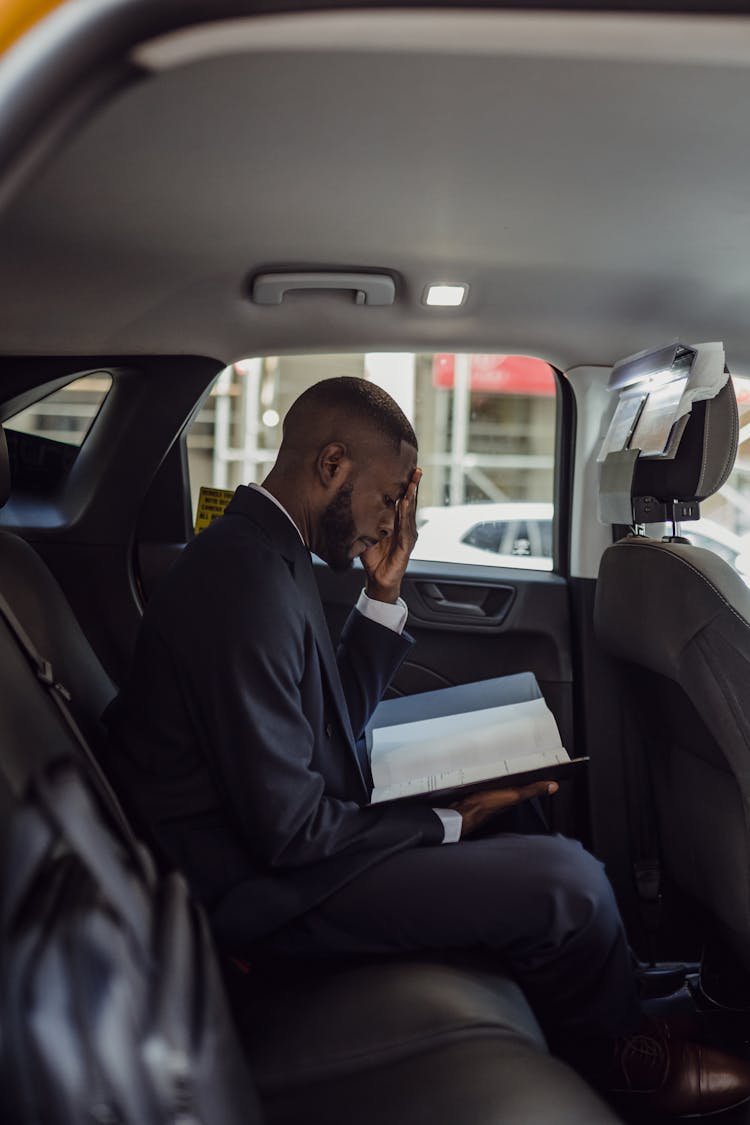 Man Sitting In A Car And Looking At Documents 