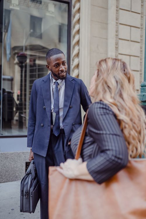 Free Two business professionals having a conversation on a busy city street, exchanging ideas. Stock Photo