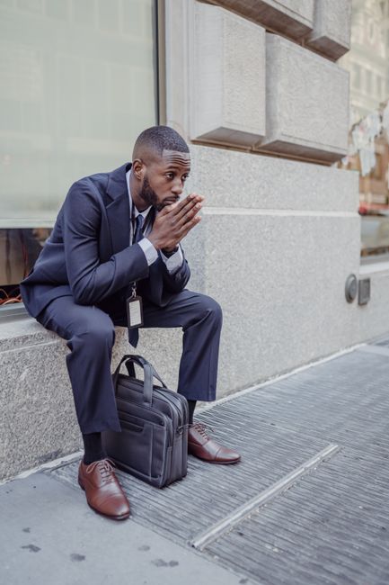 A thoughtful businessman sits on a sidewalk, contemplating his work, showcasing urban lifestyle. A thoughtful businessman sits on a sidewalk, contemplating his work, showcasing urban lifestyle.