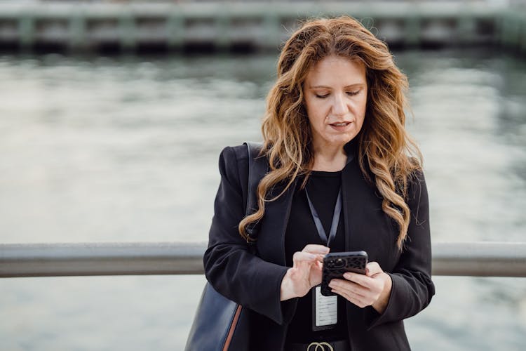 Woman Standing With A Phone On A Bridge 