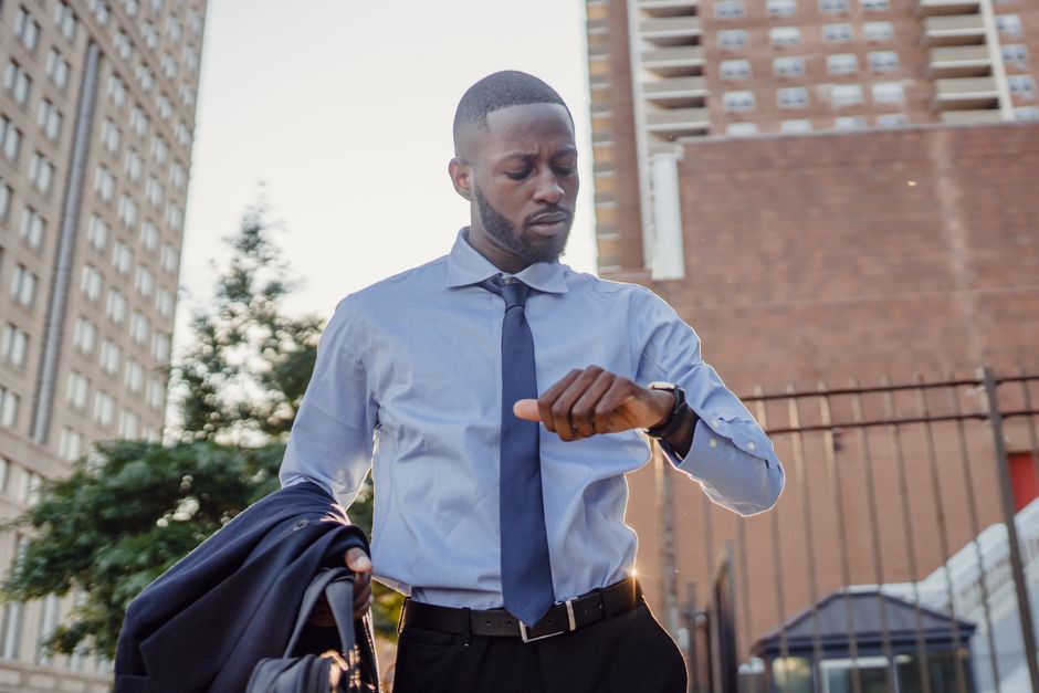 Young professional checks watch in a city backdrop, conveying urgency and business lifestyle. Young professional checks watch in a city backdrop, conveying urgency and business lifestyle.