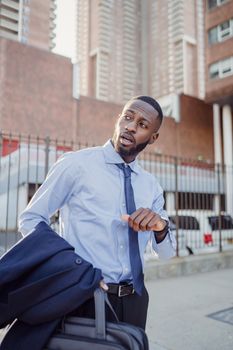 Professional man checks time while standing in urban city setting, reflecting business lifestyle.