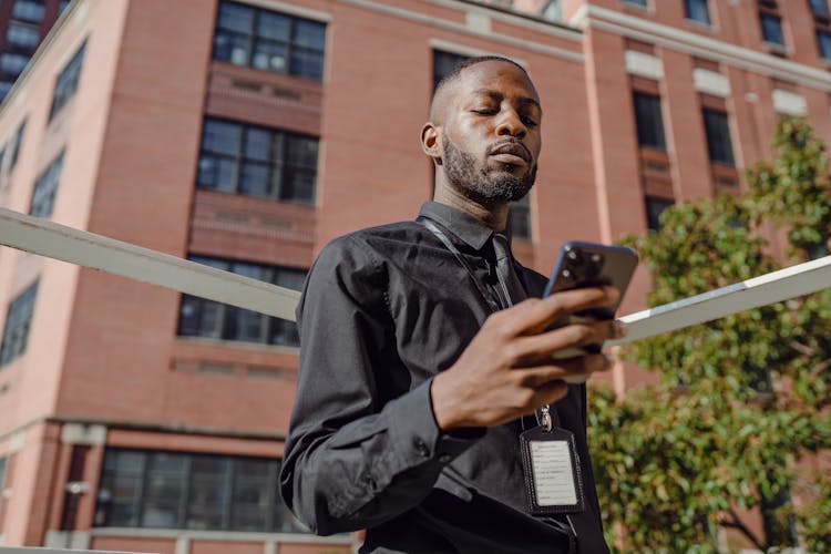 Man In Business Attire With An ID Card Using His Phone