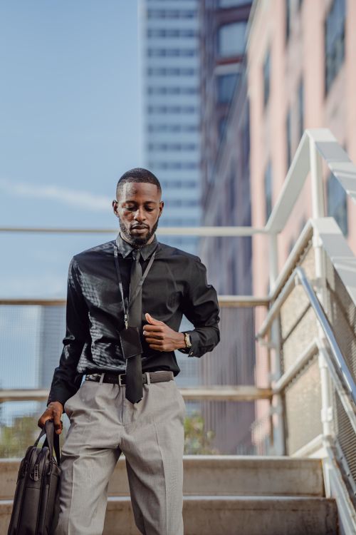 Free Businessman walking down stairs, holding a briefcase, in urban setting. Perfect for corporate themes. Stock Photo
