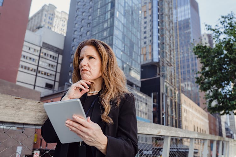 Woman Sitting, Holding A Digital Tablet And Thinking