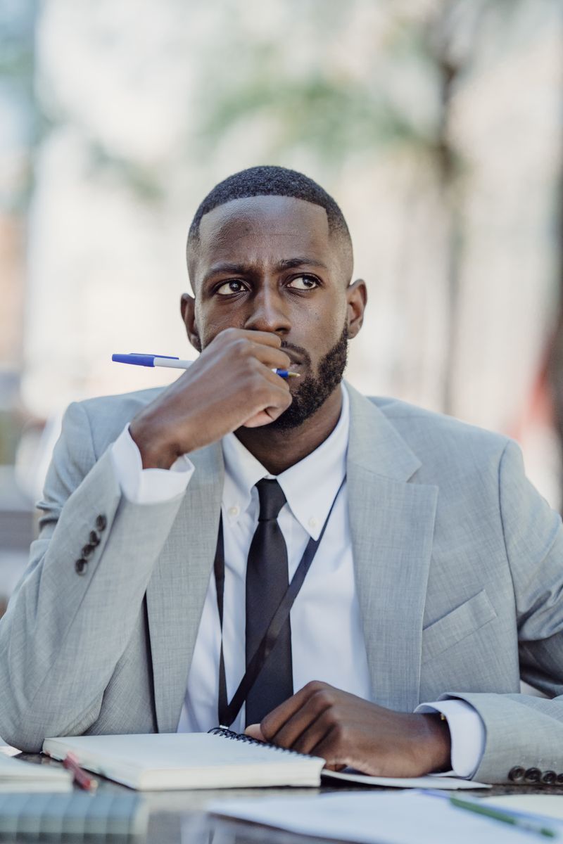 Businessman al aire libre reflexionando con pluma y cuaderno