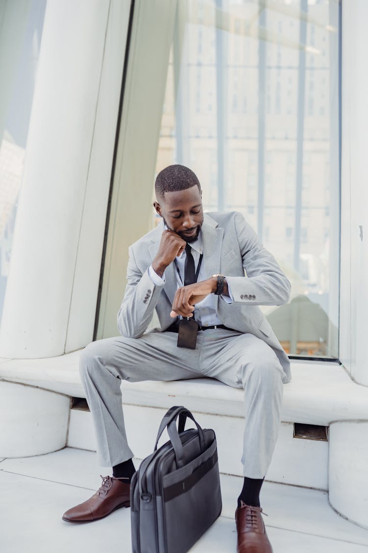 Man Sitting On A Bench And Checking The Time