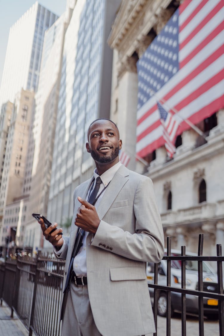 Smiling Man In A Suit Holding A Smart Phone