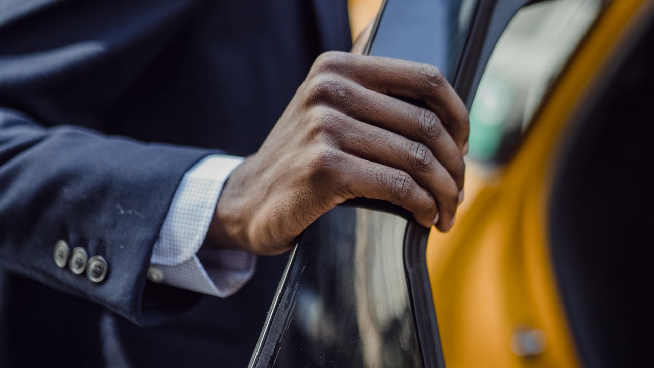 A passenger opening the door of a yellow taxi.