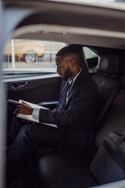 Free A business professional in a suit reading documents inside a car. Stock Photo