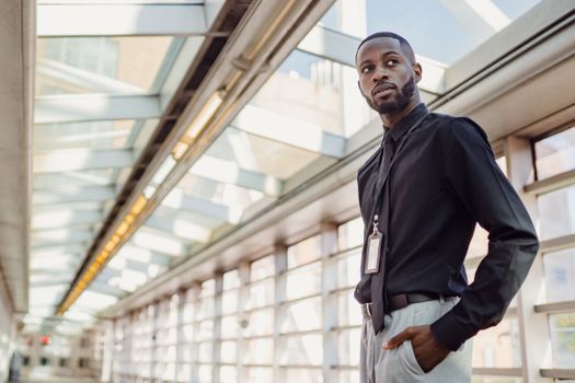 Confident young man in business attire stands in a bright, modern office corridor.